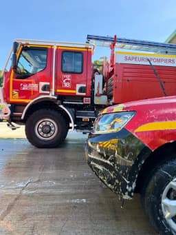 Deux camions rouges de sapeurs-pompiers stationnés devant le Centre d'Incendie et de Secours des Trois-Îlets en Martinique.